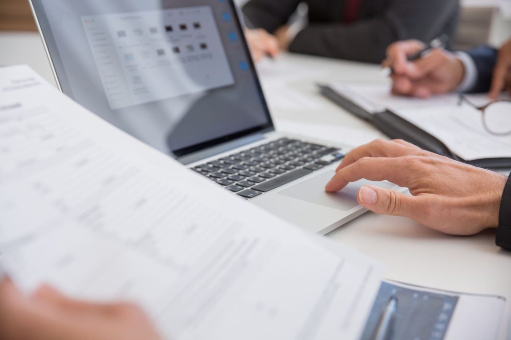 Hands working with documents and a laptop in an office
